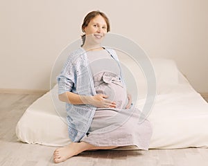 Pregnant woman sitting in living room smiling