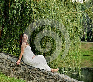 Pregnant woman sitting in the park. warm weather