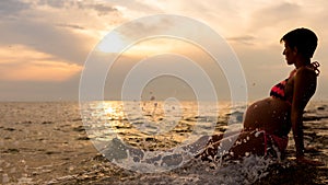 Pregnant woman sitting in the shallow water