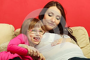 Pregnant woman sitting on sofa with daughter