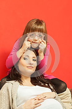 Pregnant woman sitting on sofa with daughter