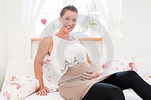 Pregnant woman sitting on sofa and smiling