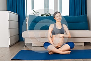 Pregnant woman sitting on yoga mat