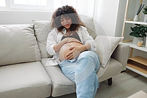 Pregnant woman smile and happiness lies on the couch freedom and strokes her belly with a baby in the last month of