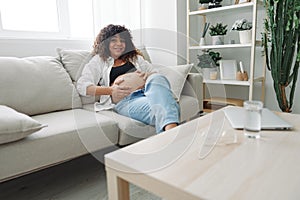 Pregnant woman smile and happiness lies on the couch freedom and strokes her belly with a baby in the last month of