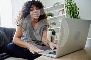 Pregnant woman smile sits at home on the couch with a laptop and talks with a doctor on video chat, freelancer works