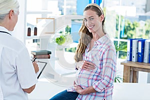 Pregnant woman smiling at camera on an examination table