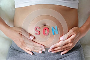 Pregnant woman with son word in front of her belly