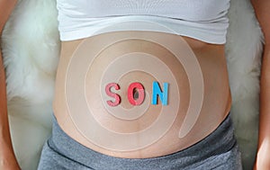 Pregnant woman with son word in front of her belly