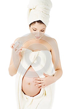 Pregnant woman in spa towels, cream for pregnancy belly