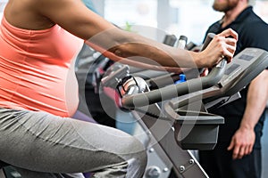 Pregnant woman spinning on fitness bike in the gym