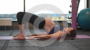 pregnant woman in sportswear exercising yoga or sports on rug in gym.