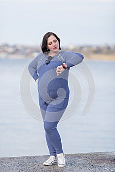 Pregnant woman in sportswear looks at her wrist watch