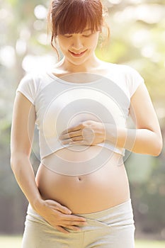 Pregnant woman in sportswear touching her big belly