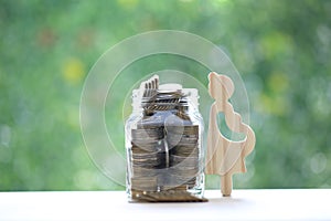 Pregnant woman with stack of coins money in glass bottle on natural green background,Save money for prepare in future and newborn