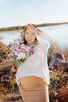 Pregnant woman standing with a bunch of flowers