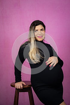 Pregnant woman standing holding baby shoes over her belly