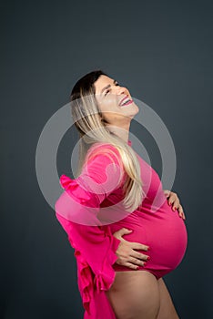 Pregnant woman standing holding baby shoes over her belly