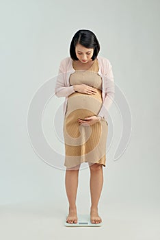 Pregnant woman standing on scales at home. Pregnancy weight gain concept