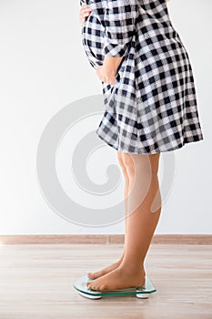 Pregnant woman standing on scales to control weight gain