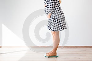 Pregnant woman standing on scales to control weight gain