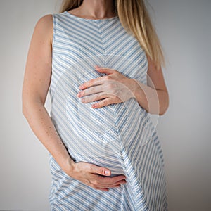 a pregnant woman stands with her hands on her stomach, the concept of expecting a baby