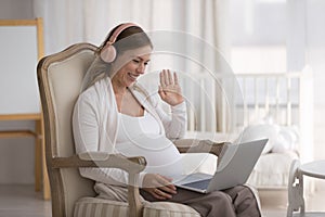 Pregnant woman start video call seated in armchair with laptop