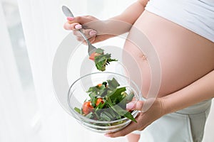 Pregnant woman starts to eat fresh salad