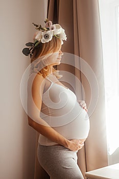 Pregnant woman stay in the room and look at the window