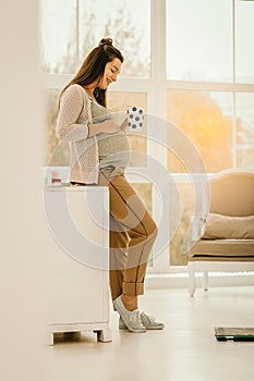 Pregnant woman staying at home and drinking tea