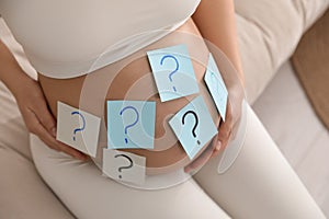 Pregnant woman with sticky notes on belly, closeup. Choosing baby name