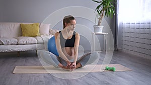 Pregnant woman stretching body and sitting on floor at home during training spbd.