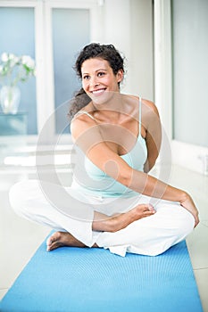 Pregnant woman stretching while sitting on exercise mat