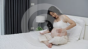 Pregnant woman stroking apply cream on her belly for beauty moisturizing skin on bed