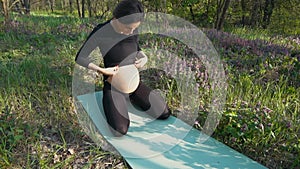 Pregnant woman stroking her baby belly sitting on grass