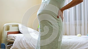 pregnant woman stroking her belly on a bed in hospital
