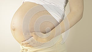 Pregnant woman stroking her belly with the hand in third trimester