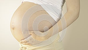 Pregnant woman stroking her belly with the hand in third trimester photo
