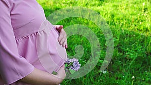 Pregnant woman stroking her belly in the park