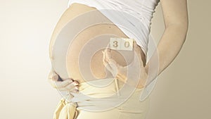 Pregnant woman stroking her belly with the pregnancy week number 30