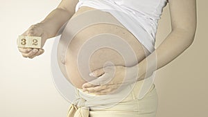 Pregnant woman stroking her belly with the pregnancy week number 32