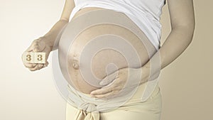 Pregnant woman stroking her belly with the pregnancy week number 33