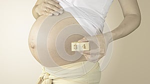 Pregnant woman stroking her belly with the pregnancy week number 34