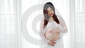 Pregnant woman stroking her belly on window background