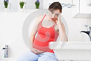 Pregnant Woman Suffering With Morning Sickness In Bathroom