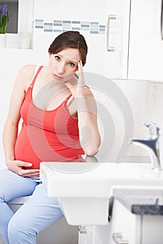 Pregnant Woman Suffering With Morning Sickness In Bathroom