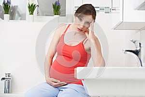 Pregnant Woman Suffering With Morning Sickness In Bathroom