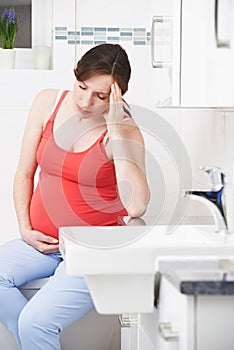 Pregnant Woman Suffering With Morning Sickness In Bathroom