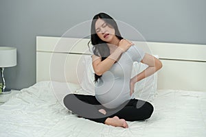 Pregnant woman suffering shoulder and lower back pain on bed