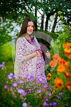 Pregnant woman in a summer scarf on her shoulders barefoot on grass